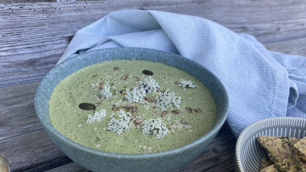grüne suppe mit kernen und blüten dekoriert in einer schale