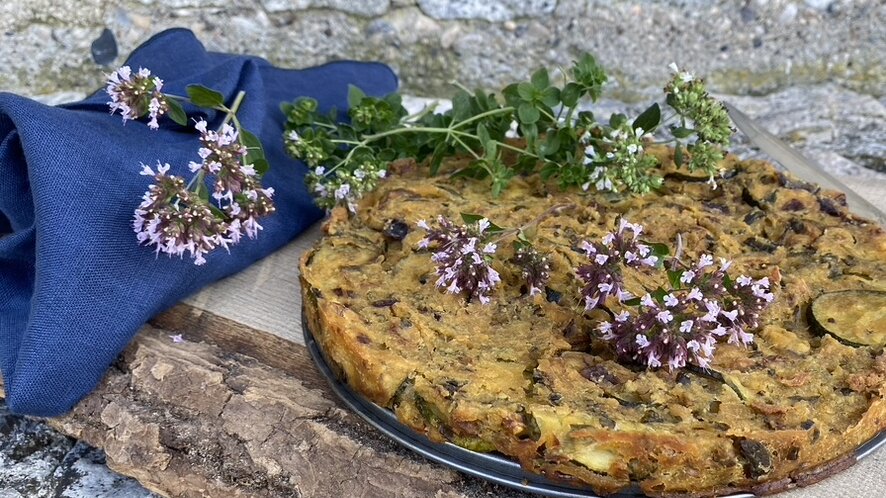gebackener gemüsekuchen mit vielen kräutern dekoriert